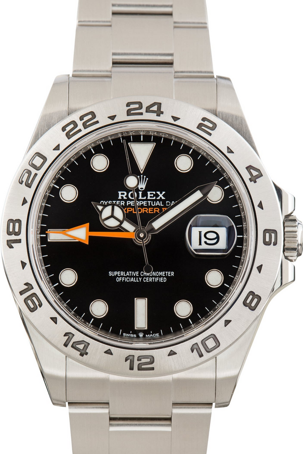A Rolex Explorer 2 watch with a stainless steel bracelet, black dial, black bezel with white indices, and an orange GMT hand.
